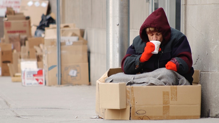 Itinérant assis dans une boîte de carton