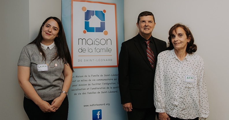 Trois personnes posant devant une affiche de la Maison de la famille de Saint-Léonard