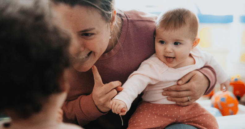 Femme avec un bébé dans les bras et souriant à une autre enfant