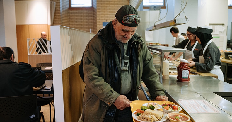 Homme avec son plateau repas dans une cafétéria